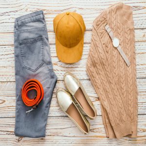 Woman Fashion set for clothing with Sweater Jeans Shoes Belt Watch and baseball cap on wooden background - Vintage light Filter